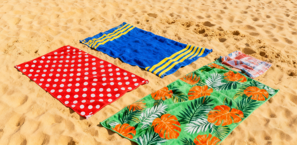 Colorful custom beach towels laid out on sand